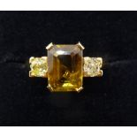An 18 carat gold ring set green/brown stone flanked by two diamonds, size K, 4.3g