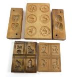 A collection of antique wooden kitchen moulds including a twin strawberry mould and three biscuit or