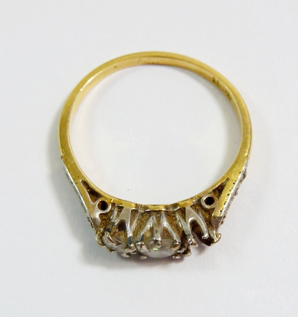 An Edwardian 18 carat gold three stone diamond ring (one stone deficient) on diamond chip shoulders, - Image 2 of 3