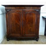 A Victorian mahogany two door linen cabinet with carved foliage decoration and arch panelled door,