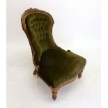 A Victorian green upholstered button back nursing chair with carved floral top rail