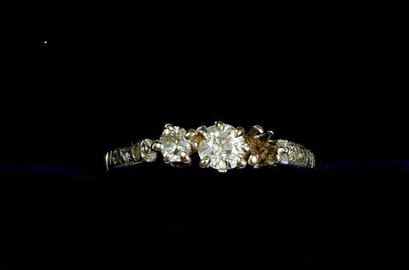 An Edwardian 18 carat gold three stone diamond ring (one stone deficient) on diamond chip shoulders,