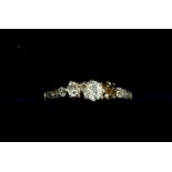 An Edwardian 18 carat gold three stone diamond ring (one stone deficient) on diamond chip shoulders,
