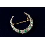 A 9 carat gold crescent moon form brooch set emeralds and diamonds, 2.5 x 2.2cm, 5.3g