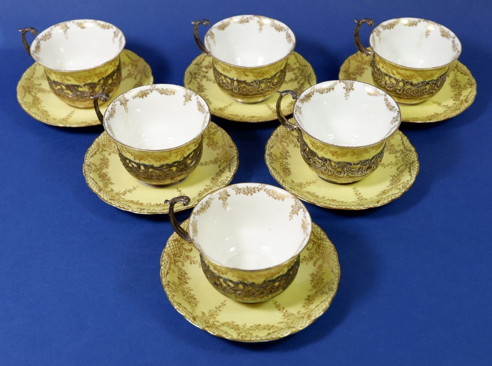 An Edwardian yellow and gilt set of six porcelain cups & saucers with silver pierced and