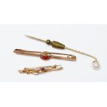 A 9 carat gold bar brooch set red stone, a gold scrollwork brooch (unmarked) and a yellow metal