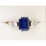 An 18ct gold ring set rectangular cut sapphire flanked by four white stones, size M to N