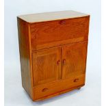 An Ercol light elm cabinet with drop front over cupboard and drawer