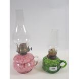 A Victorian mottled pink glass finger lamp and a green glass one