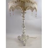 A white painted table lamp on scrollwork base, 79cm tall