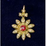 An Edwardian 9 carat gold floral pendant set red stone to centre and seed pearls to petals, 1.5cm