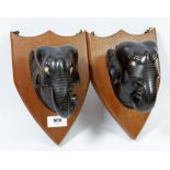 A pair of shield form ebony elephant wall plaques, 24cm tall