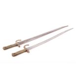 Two Chassepot bayonets, each with a 23 ins slightly curved and fullered blade, brass grips, one with