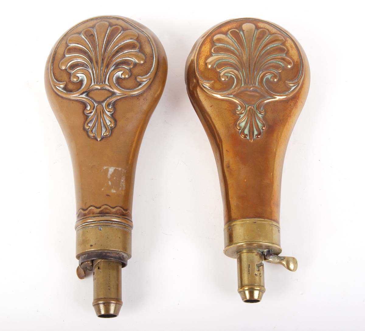 Two copper and brass powder flasks by G & J W Hawksley & Sons with embossed scroll decoration