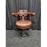 A stained beech and cast iron captain's chair, having leather circular seat on baluster cast iron