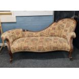 A carved walnut framed chaise longue, having floral and reeded decoration, on scroll feet