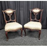 A pair of carved walnut bedroom chairs, having carved and pierced back supports, cabriole legs and