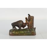 A reproduction cold painted cast iron money bank, modelled as man being chased up tree by Bison,