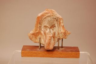 An antique terracotta artefact, 11cm wide, with head of man in headdress, possibly a fragment of a