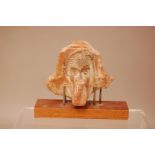 An antique terracotta artefact, 11cm wide, with head of man in headdress, possibly a fragment of a