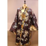 A group of textiles, including silk and embroidered kimono, a white fur shawl with silk and