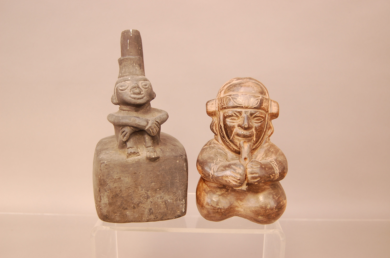 Two pre-Columbian pottery vessels, one in a material similar to basalt modelled with a man sat at