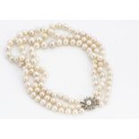 A three row knotted strung cultured pearl choker necklace, with 9ct gold flower clasp centred with