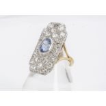 An Art Deco sapphire and diamond tablet cluster ring, the oval mixed cut sapphire surrounded by a