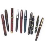 A collection of vintage fountain pens, including a black Swan self-filling, a Burnham, a brown