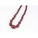 An Art Deco 'cherry amber' knotted strung graduated bead necklace, of uniform semi opaque red/