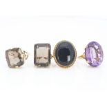 A collection of four 9ct gold gem set dress rings, the large amethysts and smoky quartz set in