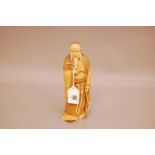 A Japanese late Meiji period carved ivory figure of an elder, 21cm, well worked and signed to