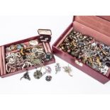 A collection of costume jewels in a red case, hinged lid opens to reveal a collection of jewels
