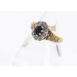 An 18ct gold sapphire and diamond cluster ring, the oval mixed cut sapphire in claw setting