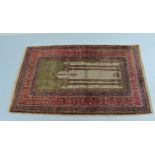 A Middle Eastern woollen prayer mat, centred with arched panel within a multiple bordered frame