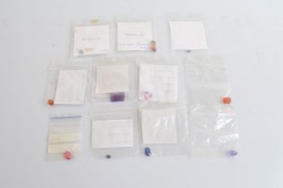 A collection of loose various gemstones, including tourmaline, garnet, sapphire, amethyst,