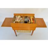 A continental pine and beech sewing table, with hinged panels, fitted interior and slide out basket,