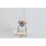 A Ceylon sapphire and diamond 18ct gold cluster ring, the cushion cut claw set sapphire surrounded