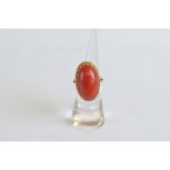 A continental yellow metal and precious coral dress ring, the red polished coral in wavy flange