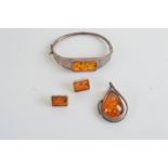 An amber and silver bangle, 6.2cm x 4.5cm together with a pear shaped amber pendant and a pair of