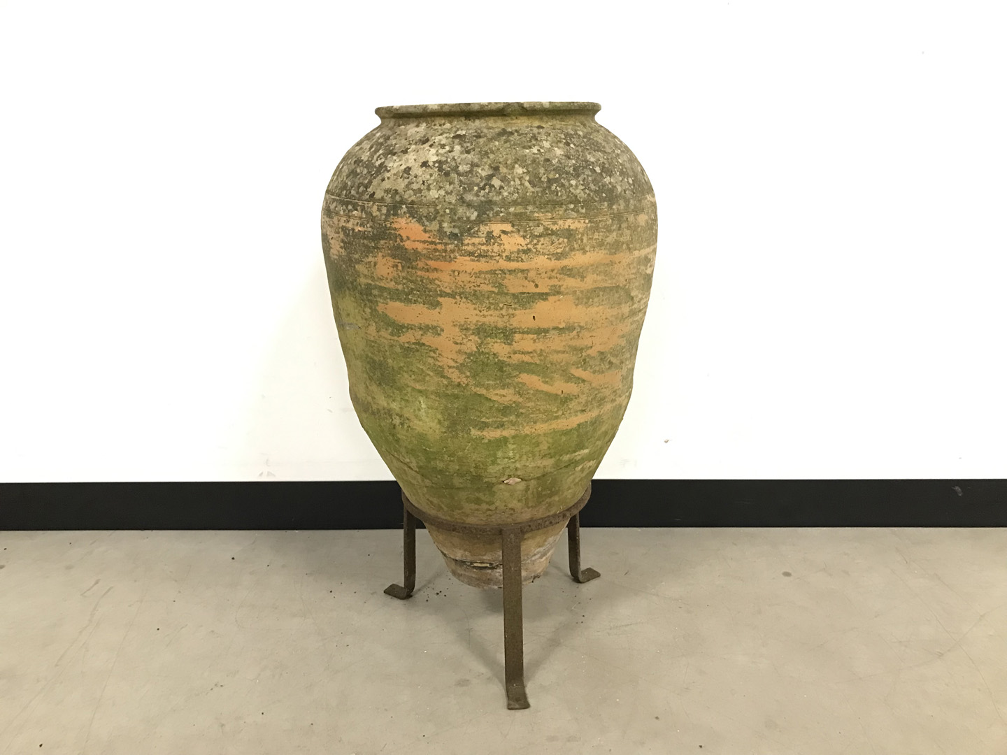 A second half 20th century terracotta plant pot, AF, cracked, on a wrought iron tripod stand, 75cm