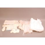 A collection of late 19th/early 20th century dolls clothing, including a knitted cardigan, gloves
