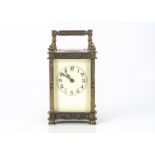 An Edwardian brass carriage time piece, 14.8cm high with handle raised, cream enamel dial with