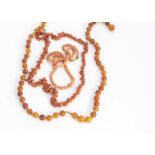 An amber spherical bead knotted strung necklace, graduated shape, together with a coral bead