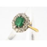 A 18ct gold emerald and diamond cluster ring, oval mix cut emerald in claw setting surrounded by ten