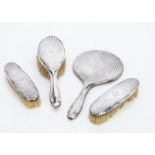 A George V silver dressing table set, comprising hand mirror, hair brush and pair of clothes brushes