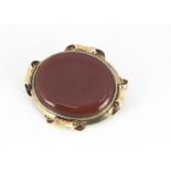 A Victorian yellow metal and red hardstone mourning brooch, 55mm wide, the oval frame supporting a