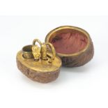 A 19th century walnut sewing etui, the nut shell in two halved and hinged to open to reveal
