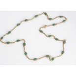 A 585 marked yellow metal and emerald necklace, the mix oval cut stone, alternately set with