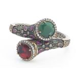 A continental past set hinged bangle, of crossover design set with red, green synthetic gem stones